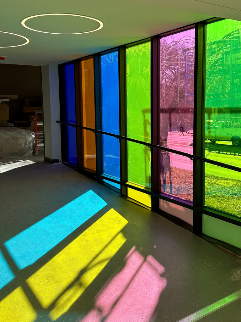 sun shining windows with bright colored film, reflecting bright colors onto the floor