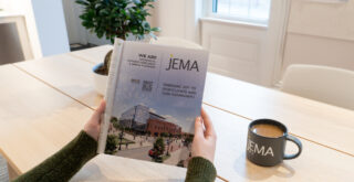 image of person holding a magazine with whole page JEMA ad printed